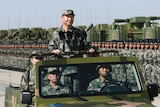 Chinese President Xi JinPing stands on a military jeep in full camouflage gear