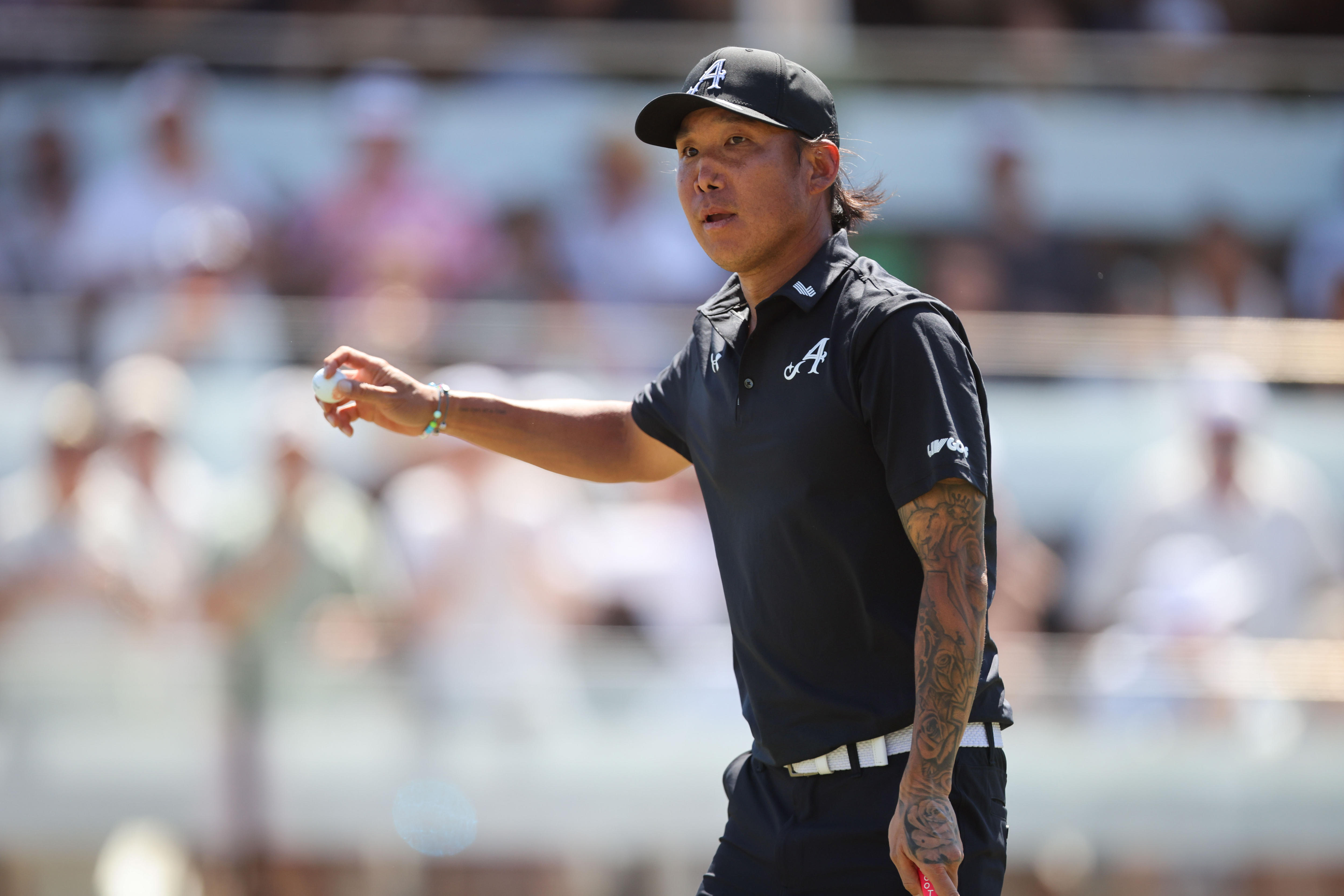 Golf thanking fans for applause, raising his arm with the golf ball in hand