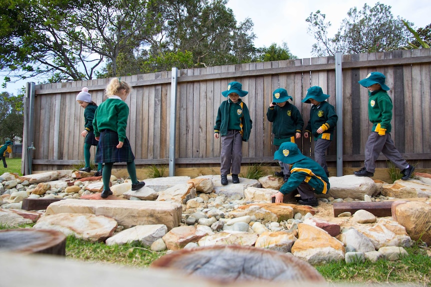 School students play on rocks.