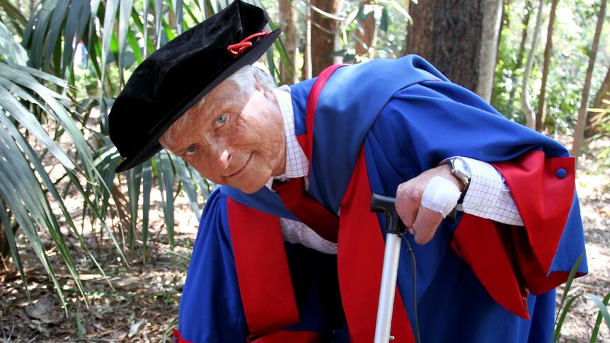 Dr Robert Sawyer crouches in bushland near Wollongong