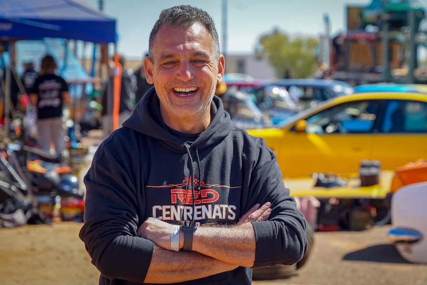 Smiling man in front of cars