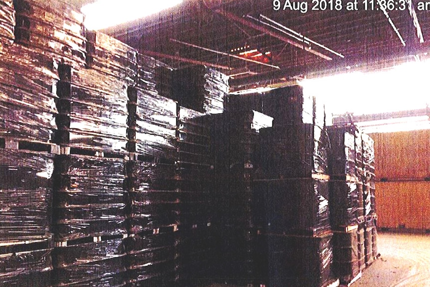 Crates wrapped in plastic are stacked up inside a warehouse.