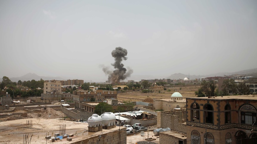 A long shot shows buildings and smoke rising in the distance.