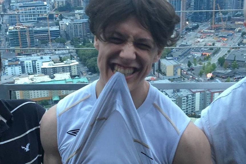 a young man biting his white t-shirt 