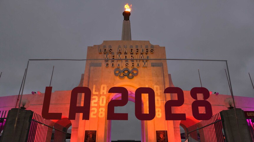 An LA2028 sign is seen in front of a blazing Olympic cauldron at the Los Angeles Memorial Coliseum.