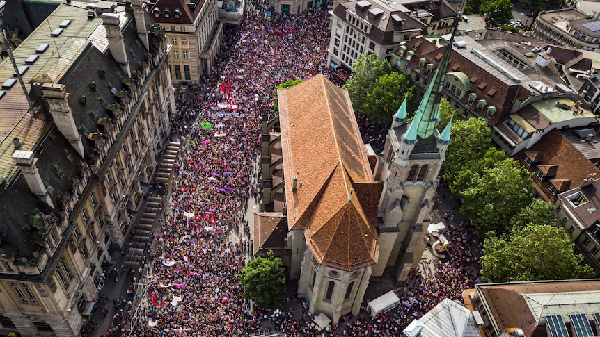 An aerial shot of a church surrounded by thousands of people holding flags and banners.