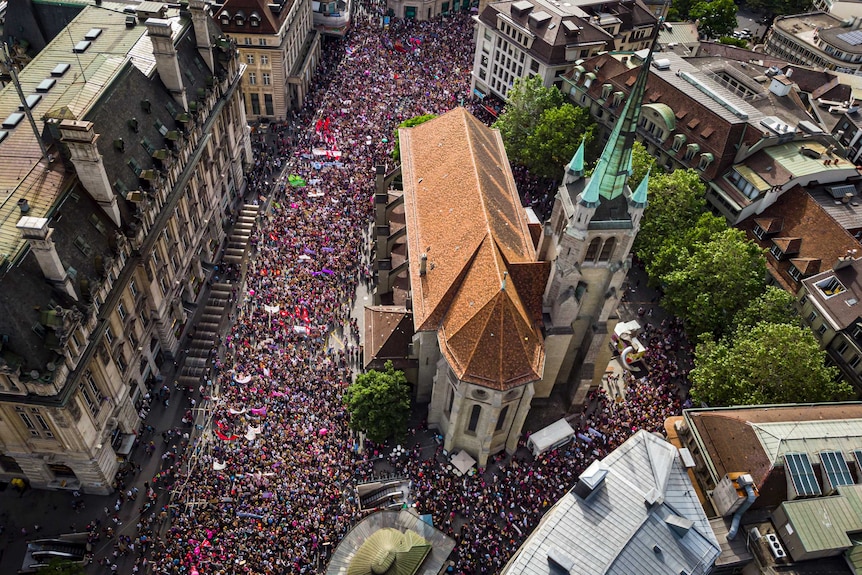 An aerial shot of a church surrounded by thousands of people holding flags and banners.