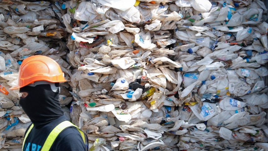 Stacks of flattened milk cartons and plastic containers are piled up