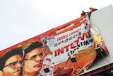 Workers remove the poster for The Interview from a billboard in Hollywood, California, December 18, 2014