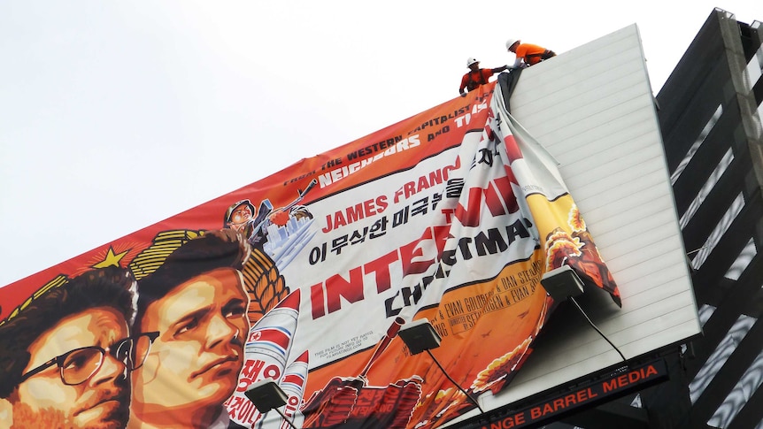 Workers remove the poster for The Interview from a billboard in Hollywood, California, December 18, 2014