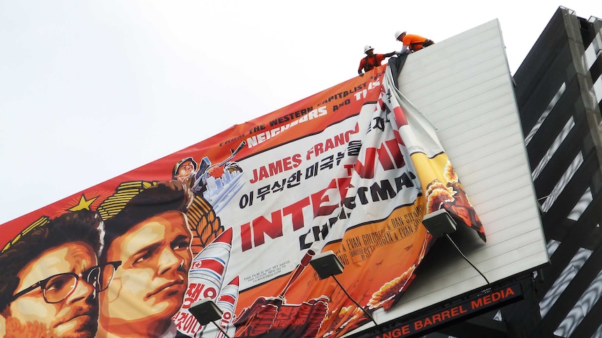Workers remove the poster for The Interview from a billboard in Hollywood, California, December 18,