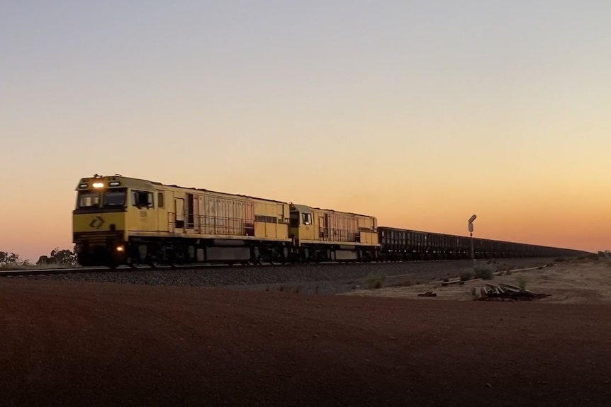 A freight train in low lights, crossing the desert.