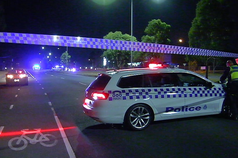 Police cars parked on a taped off multi-lane road.