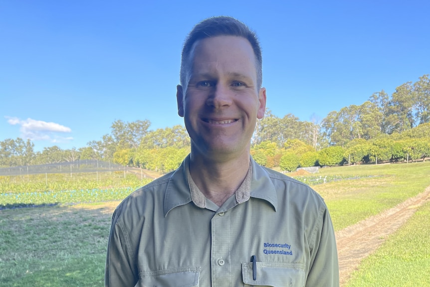 A man wearing a khaki shirt smiling 