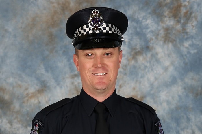 Constable Glen Humphris smiles as he poses for a portrait photograph in his police uniform.