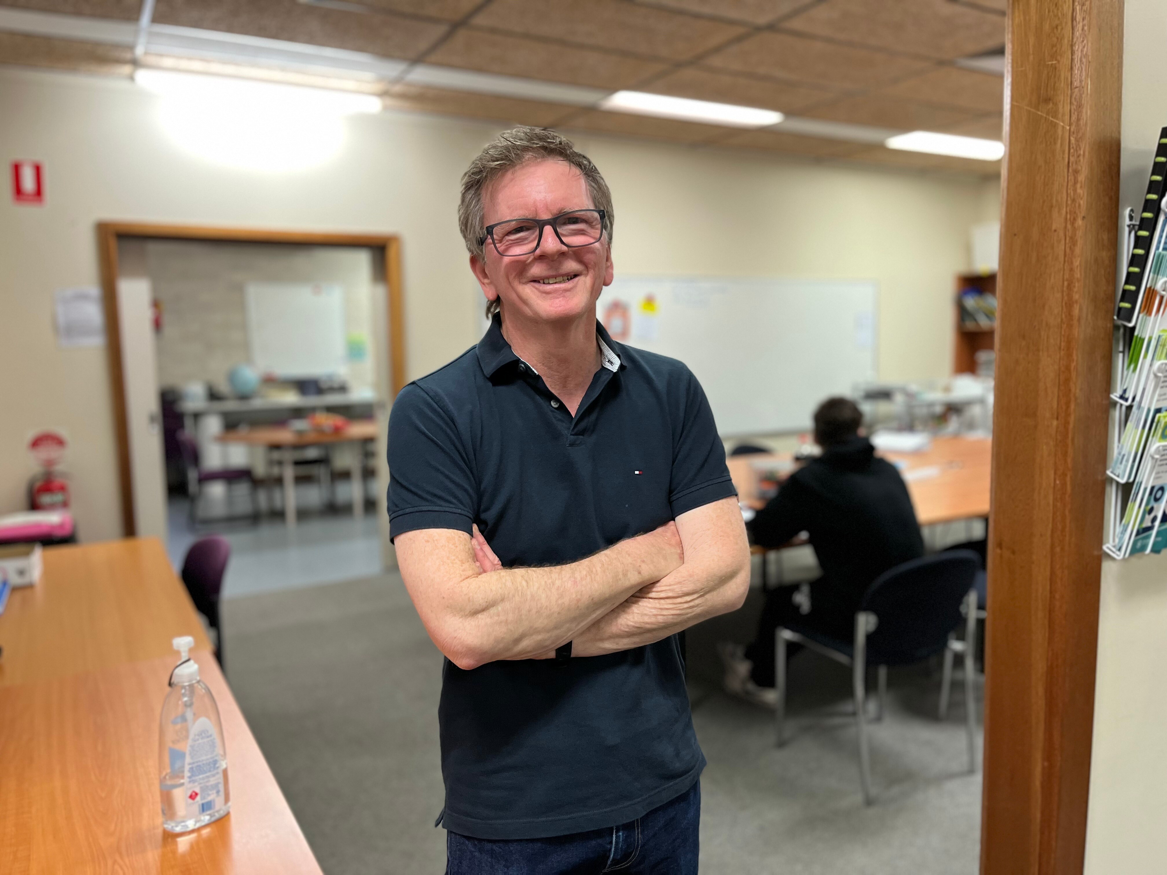 A man with glasses wearing a polo shirt in a room