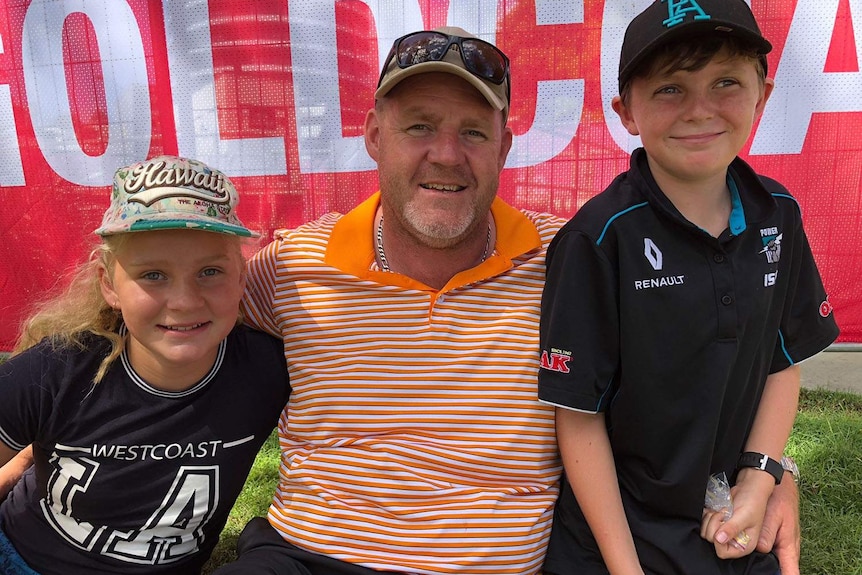 Brisbane resident Andrew Paterson with his two children Hamish, 10, and Rennah, 12, sit in a park on Queensland's Gold Coast