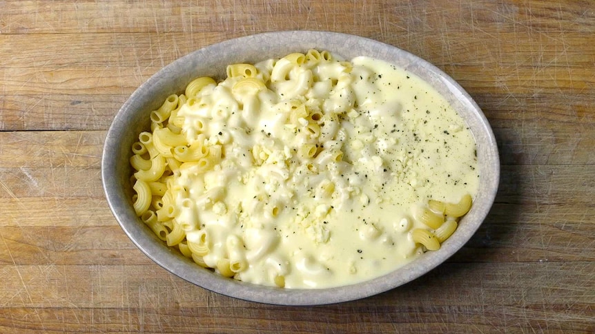 Bird's eye photo of a mac and cheese with crumbly cheddar sprinkled over the top.