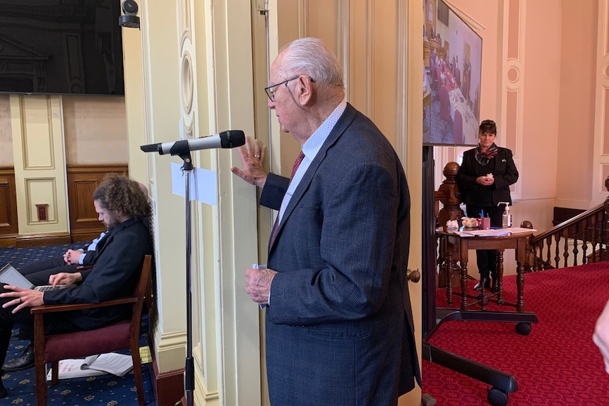 Elderly man speaking into a microphone in the Launceston Council Chambers