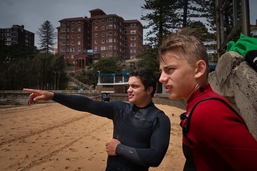 Two young male surfers look out to sea.