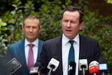 Mr McGowan speaks in front of a clutch of microphones, WA Health Minister Roger Cook looks on.