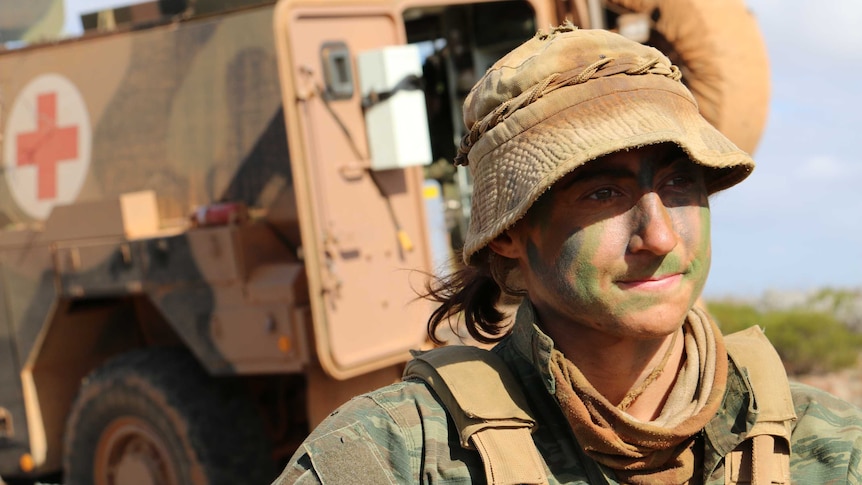 Corporal Rachel Benson dressed in Army uniform in front of a medical vehicle.