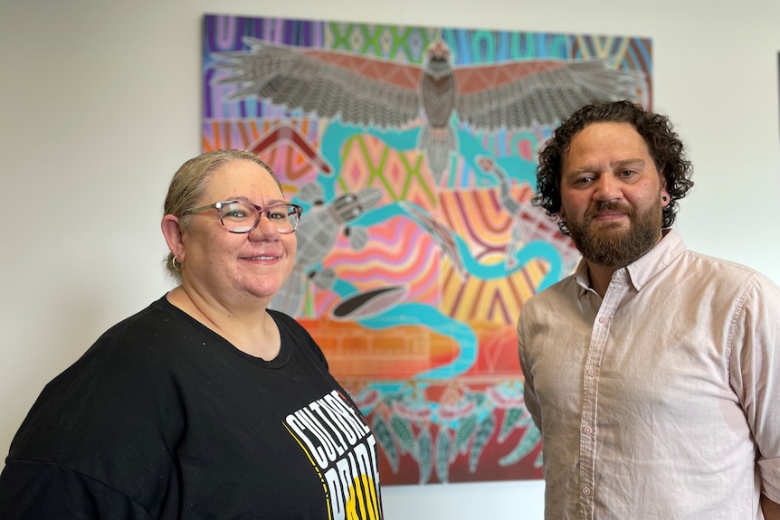 A woman and man standing in front of a painted artwork