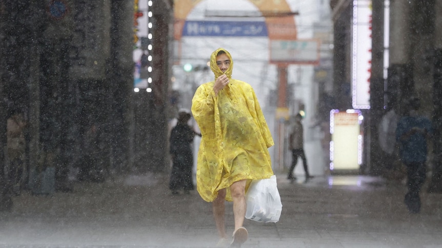 man walks in rain japan typhoon