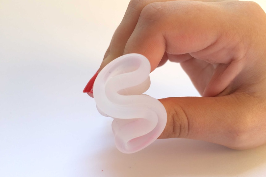 A hand holding a menstrual cup that's folded for insertion