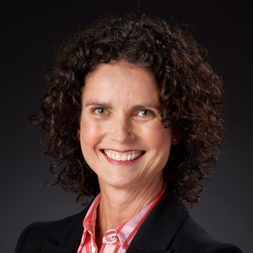 A woman with brown curly hair wearing a black blazer