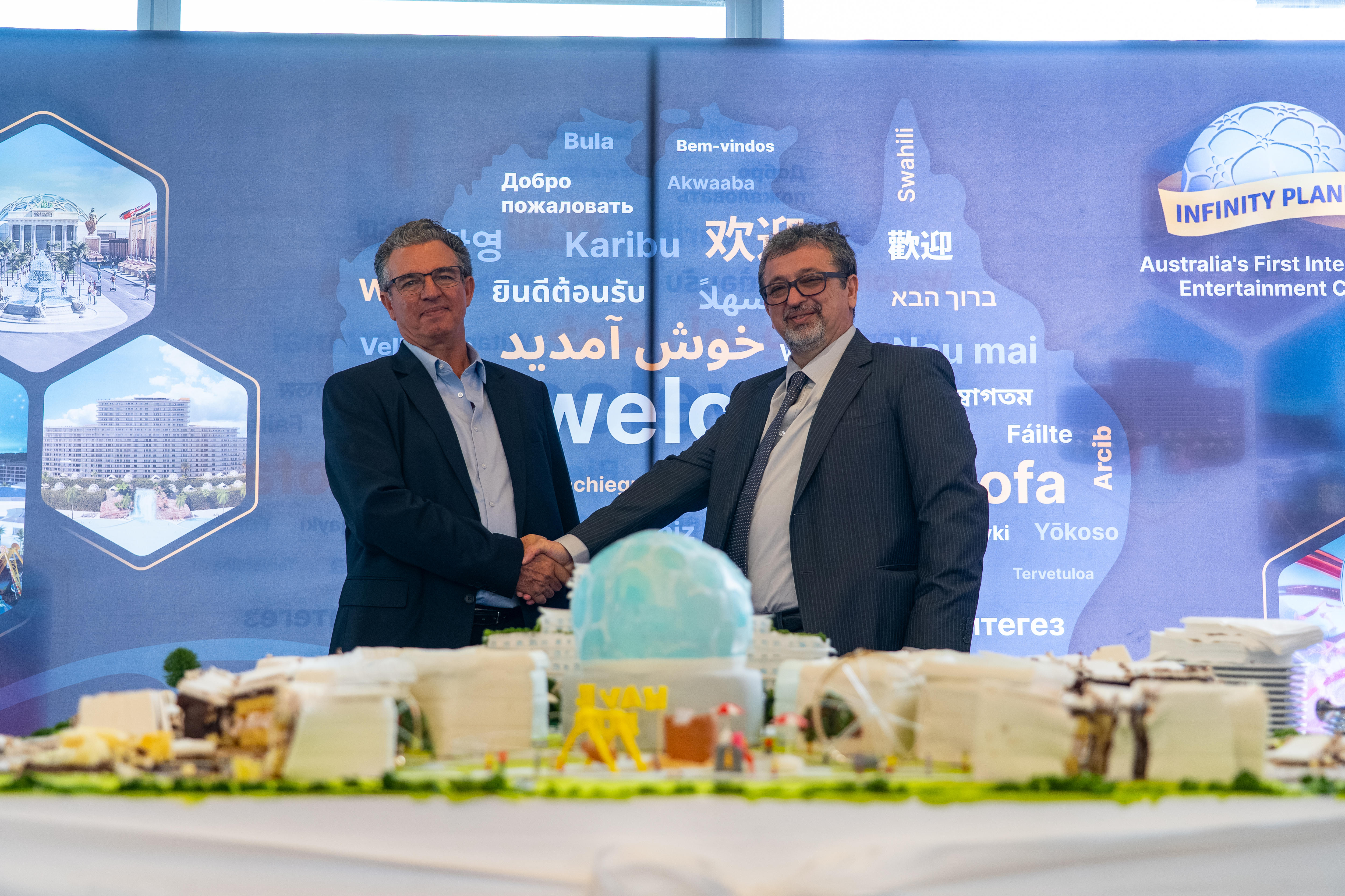 Dos hombres se dan la mano frente a una maqueta de una ciudad