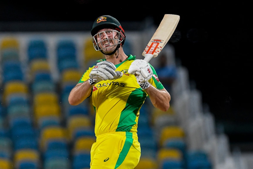 A smiling Australian batsman takes his hand off the bat as he looks skywards after hitting a six.