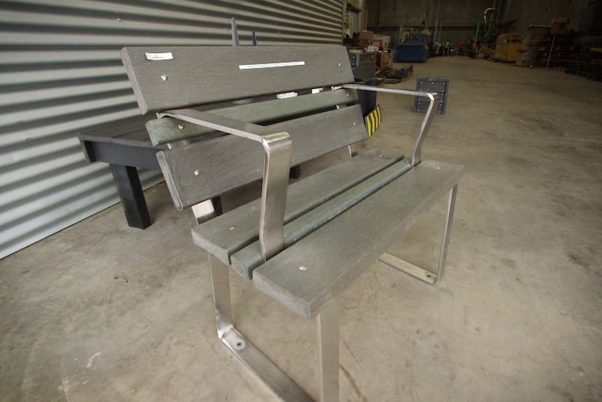 A grey bench sits on the floor of a factory