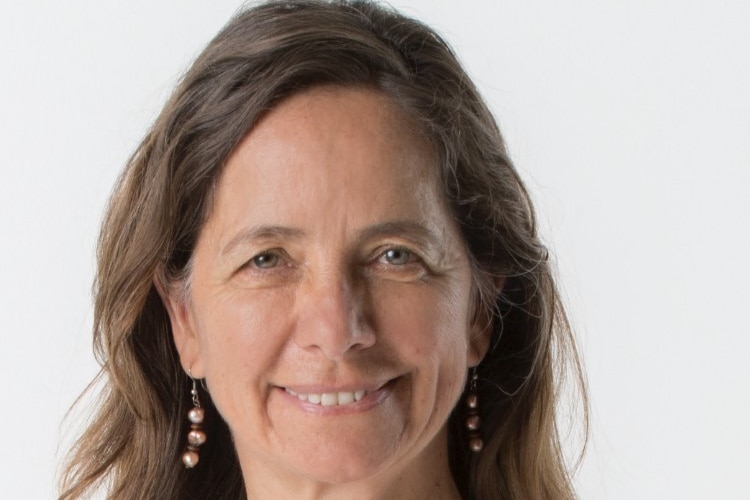 Middle aged woman smiling in a white and pink shirt