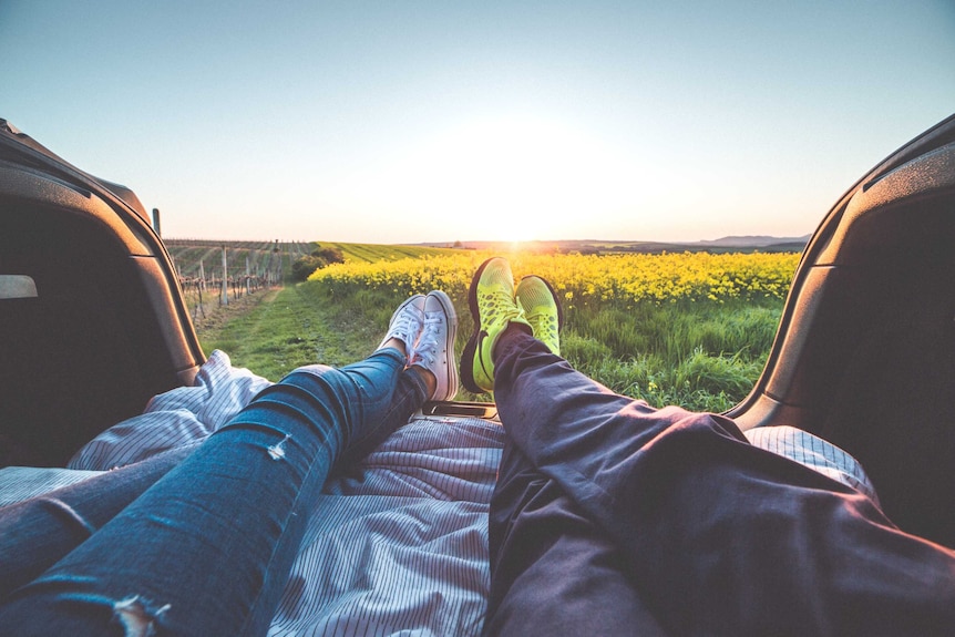 Couple relax in the back of their car looking at the view to depict a story about women experiencing baby panic.