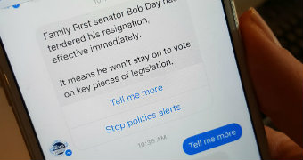 A close up photo of a person holding a phone with an ABC News Facebook Messenger alert about Bob Day's Senate resignation.