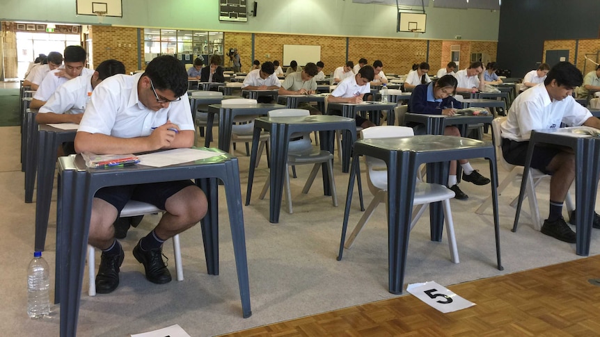 Seated in rows are year 12 Corpus Christi college in Bateman sit the 2014 physics exam