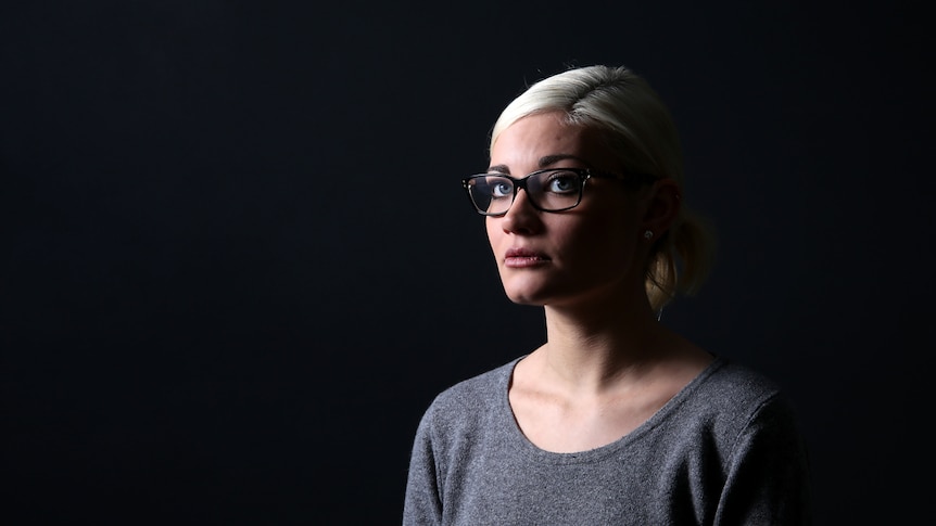 Anna Chaplin stands in a dark room.