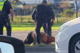 A still from a video shows police officers standing over a man on the ground.