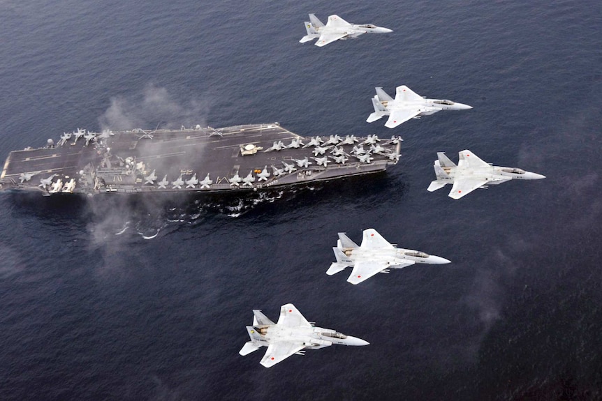 Japan Air Self-Defence Force F-15 fighter jets fly over US Navy aircraft carrier USS Carl Vinson in the Sea of Japan.