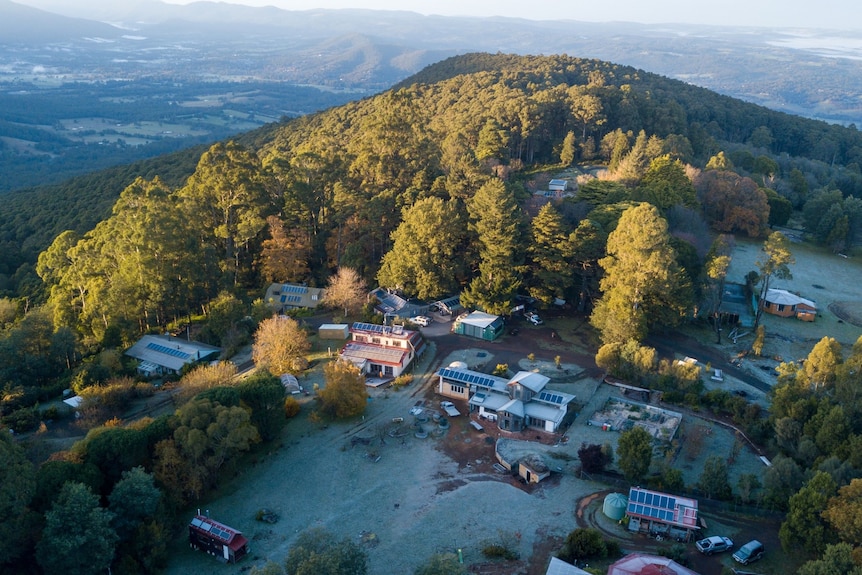 An aerial image of a small community on a hilltop surrounded by forest.