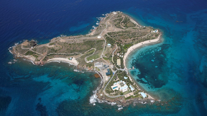 A small island surrounded by blue water with a mansion on it.