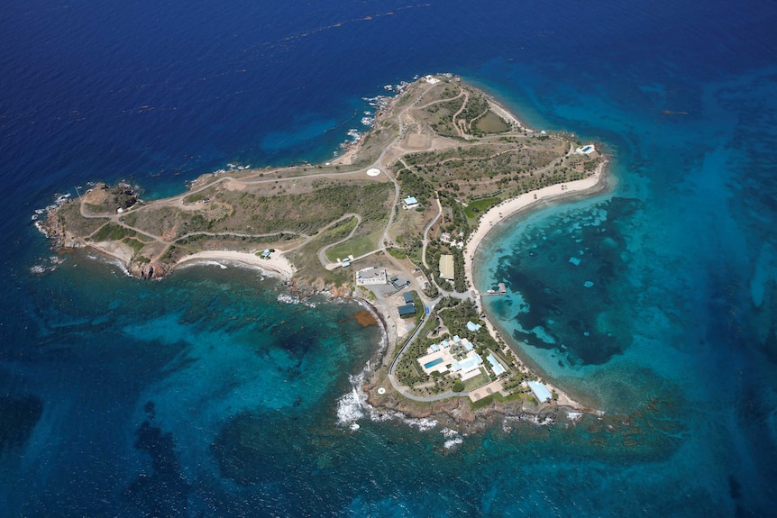 A small island surrounded by blue water with a mansion on it.