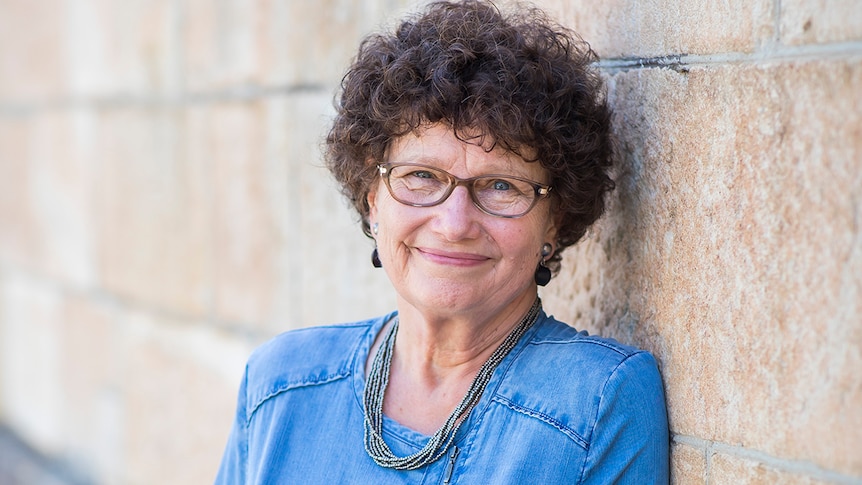 Colour photo of author Vicki Laveau-Harvie smiling and leaning against sandstone wall.