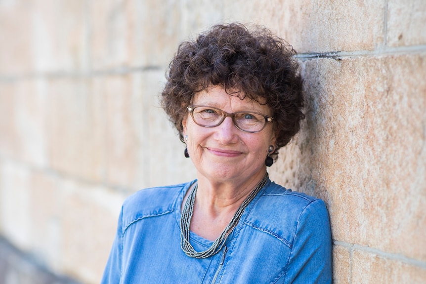 Colour photo of author Vicki Laveau-Harvie smiling and leaning against sandstone wall.