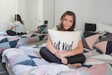 Monique Mastrobattista sitting on her bed with a Get Kind cushion