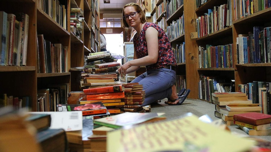 Sam Colwell removes water-damaged books from the shelves at Archives Fine Books in the Brisbane CBD