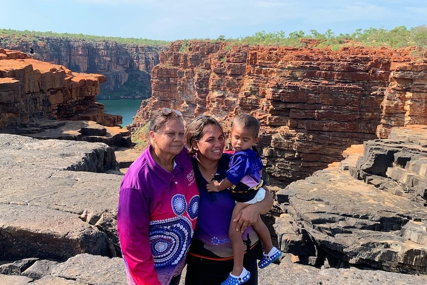 Two women, one holding a baby, stand near King George Falls.