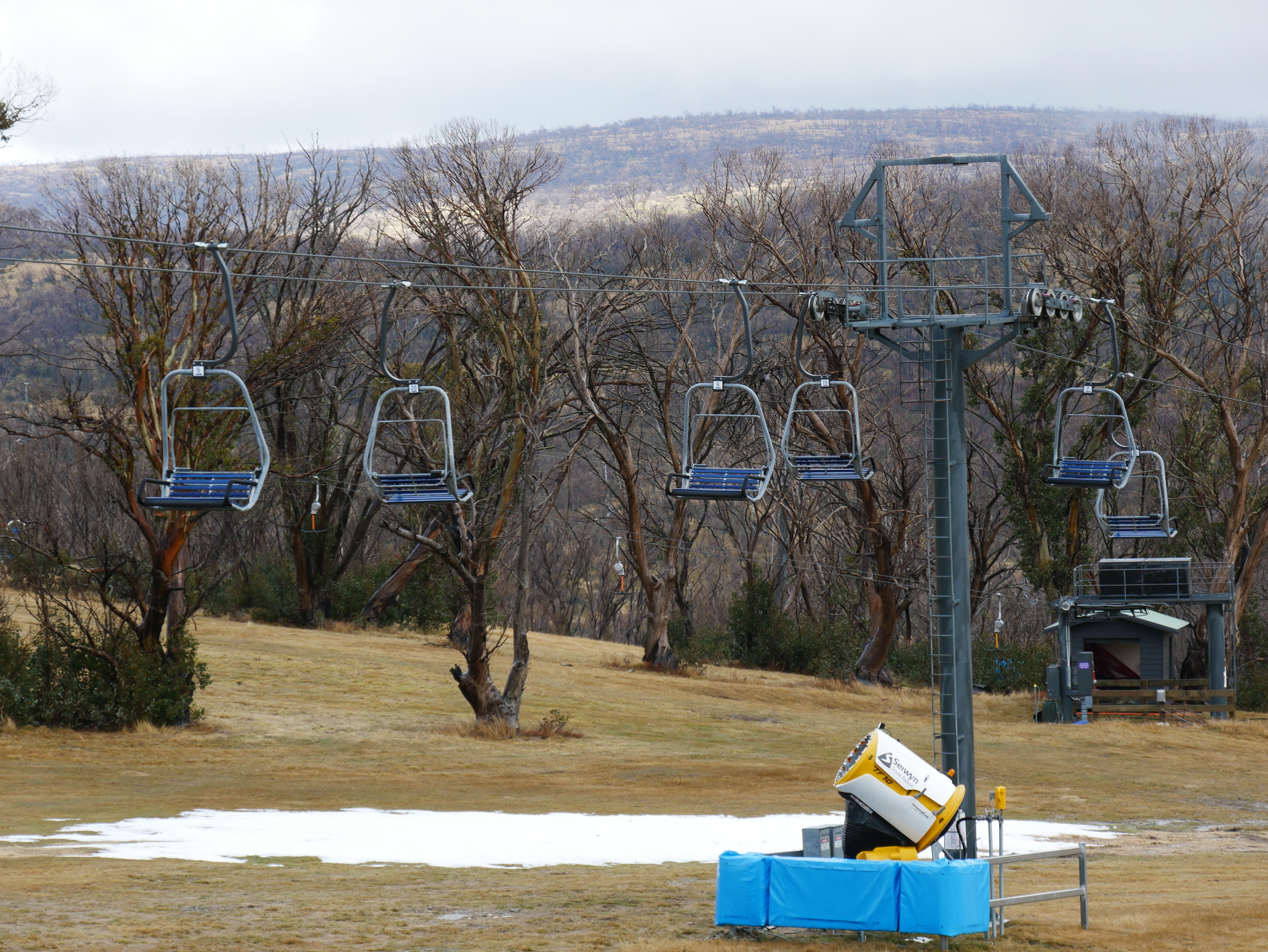 A chairlift at a snow resort with little to no snow.