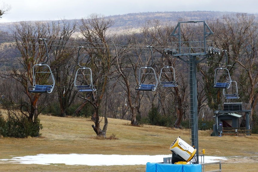A chairlift at a snow resort with little to no snow.